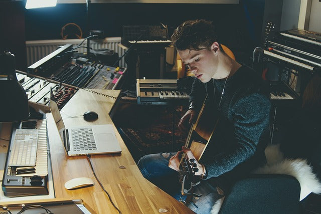 Studio man sat at desk with guitar